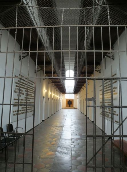 Looking down a hallway lined with prison cells.