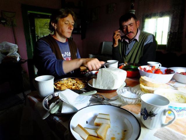 Ileana finally gets to eat as Dinu talks on his cell phone. The slices of lard can be seen in the foreground.