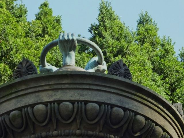 A poor photo of the three hands grasping the circle or wheel. 