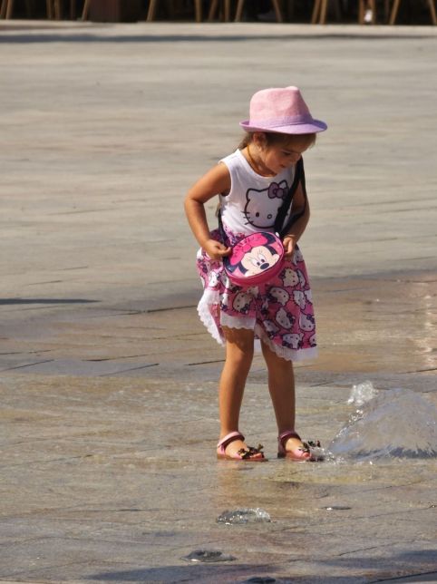 Little girl having fun in the unpredictable spouting water 
